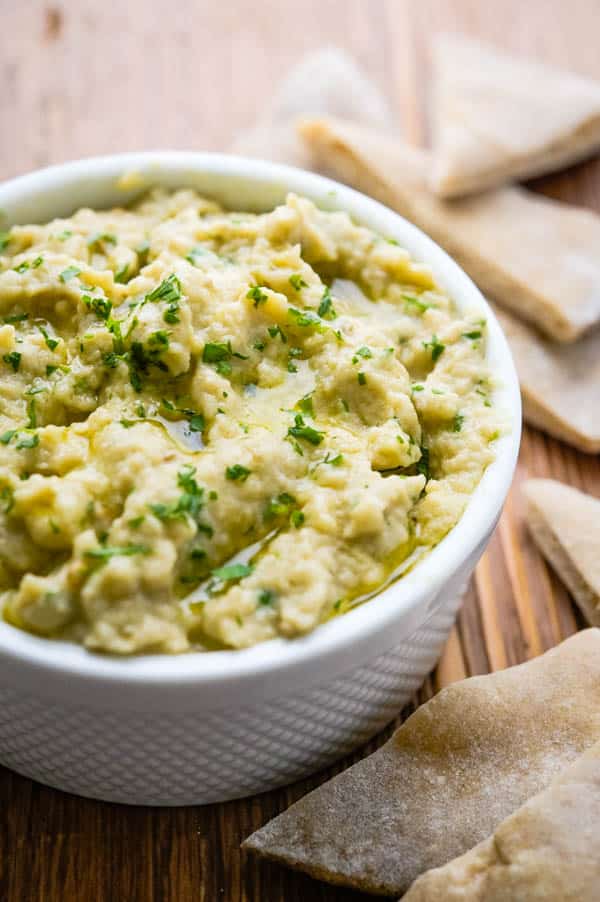 a bowl of eggplant dip with pita chips.