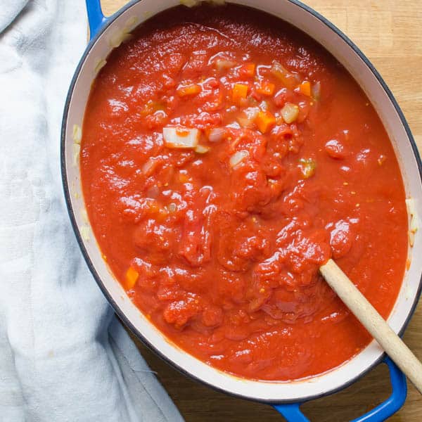 The marinara sauce in a pot with a spoon.