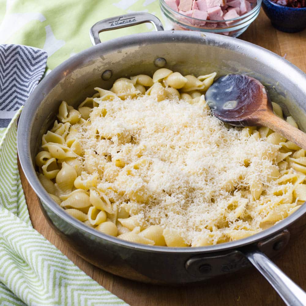 Tossing pasta in creamy lemon sauce and sprinkling with grated Parmesan.