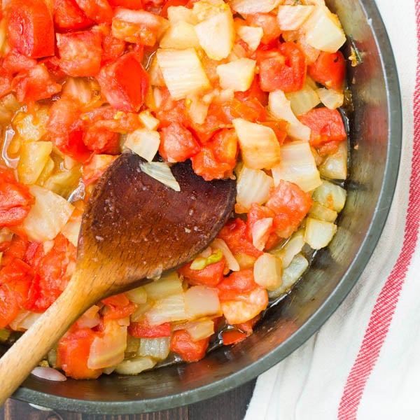 tomato fennel ragout in a pan with wooden spoon.
