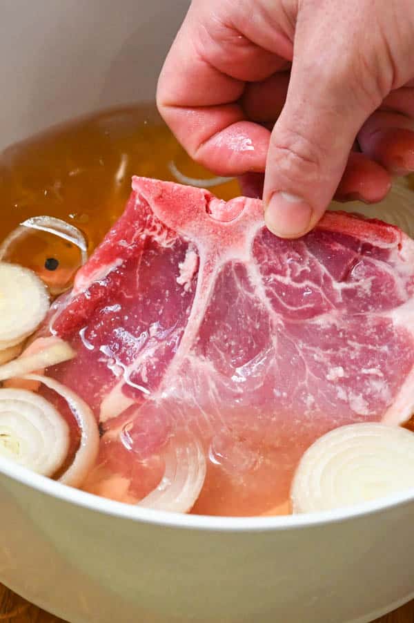 adding pork chops to the brining solution.