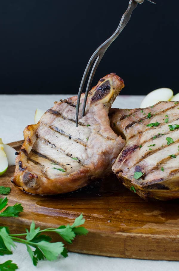 Brined Grilled Pork Chops on board with meat fork.