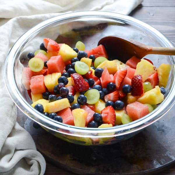 cut fruit in a bowl with a wooden spoon