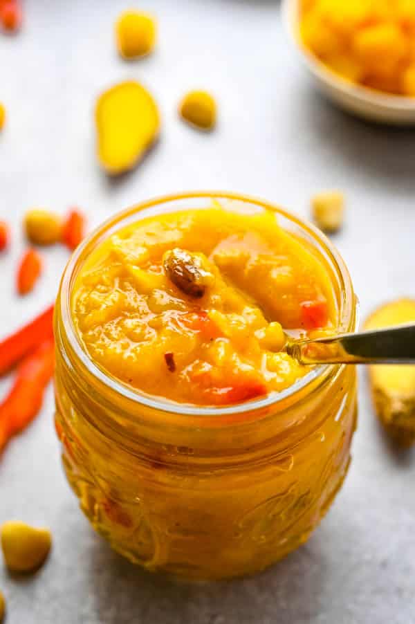 a jar of curried chutney with a spoon.