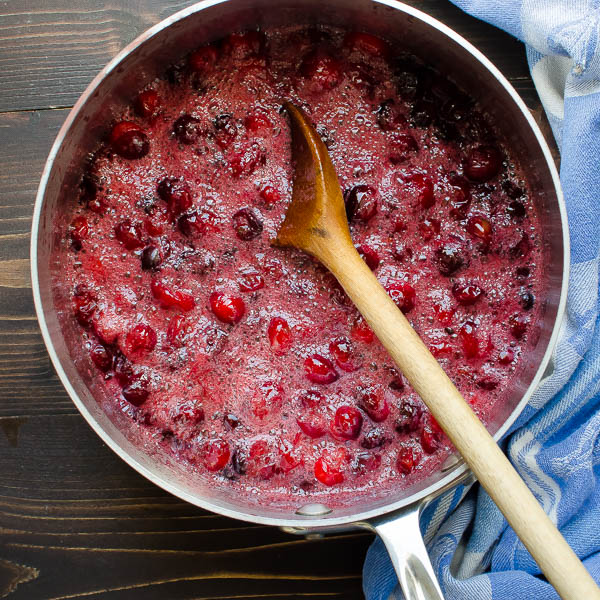 cranberry sauce cooking in a pot with wooden spoon.