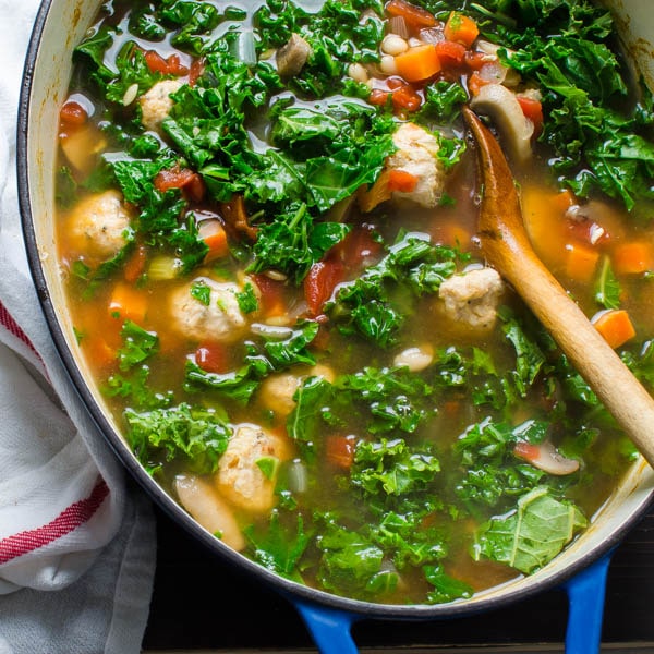 Kale, White Bean and Meatball Soup with wooden spoon