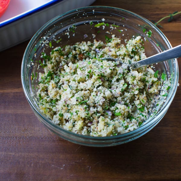 breadcrumbs and herbs mixed together in a bowl with a spoon.