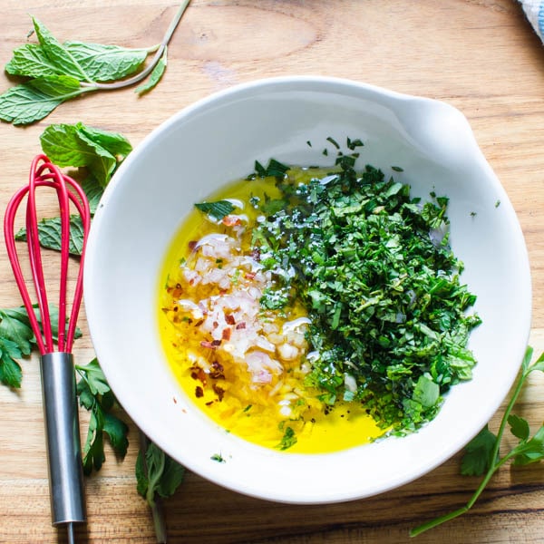 Making mint chimmichurri with herbs, shallots, oil and vinegar.