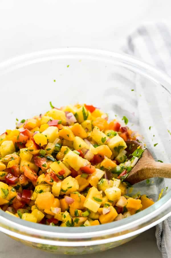mixing tropical salsa with a wooden spoon.