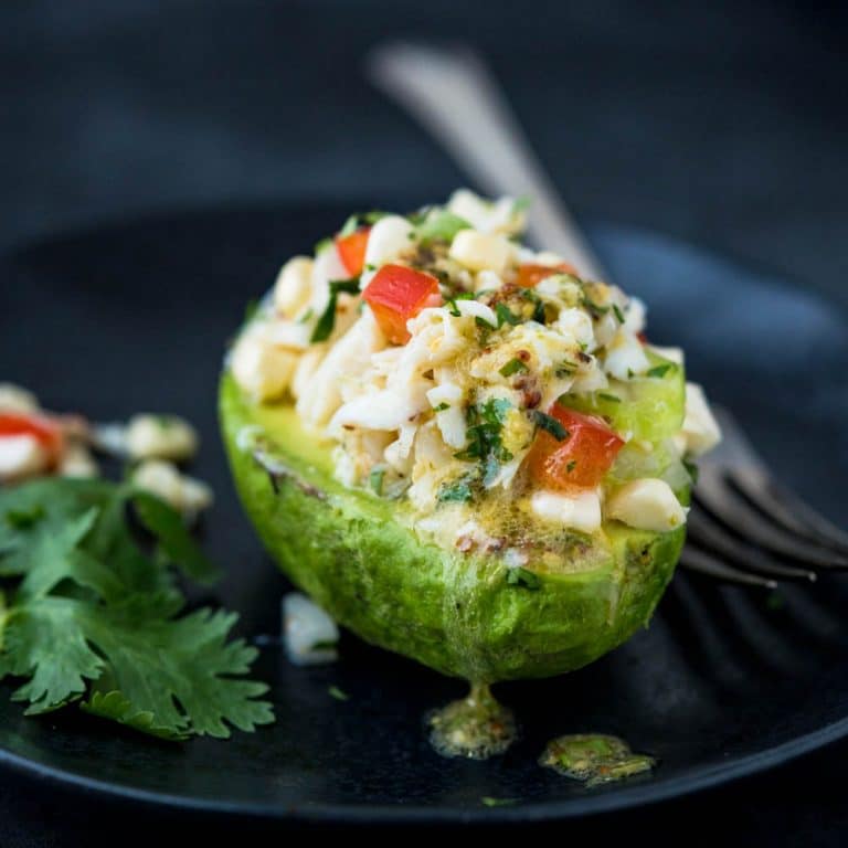crab avocado salad with extra dressing on a plate.