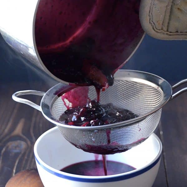 straining the blueberry sauce.