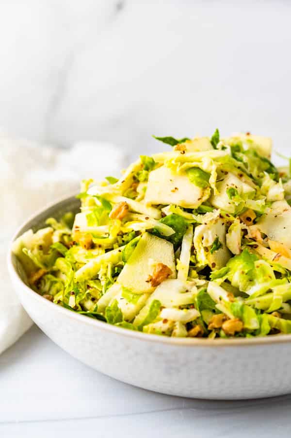 a mound of apple fennel slaw with toasted walnuts in a serving bowl. 