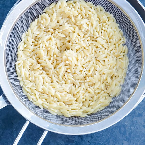 cooked orzo in a strainer.