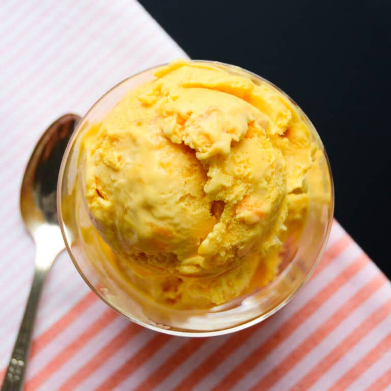 A dish of coconut mango ice cream with a spoon.
