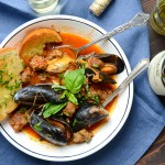 A dish of mussels and sausage with bread for dipping.