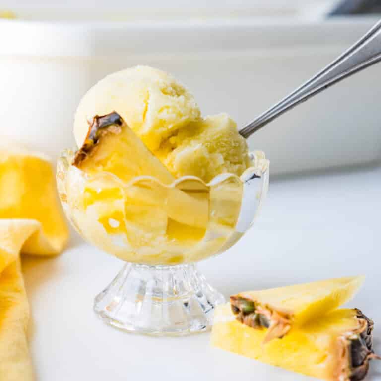 a footed dish filled with a scoop of pineapple sorbet.
