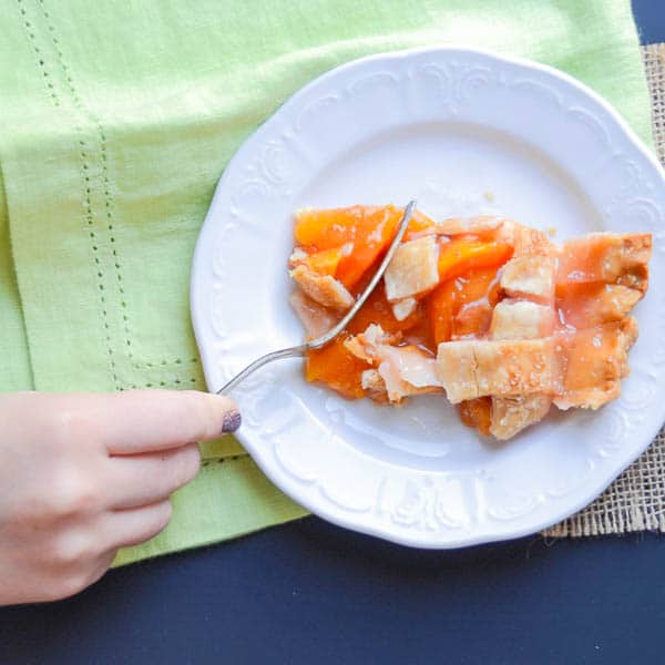 A slice of Fresh Peach Pie with Lattice Crust and a fork.