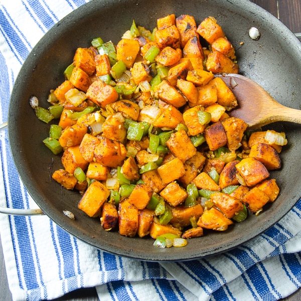 sweet potato hash in pan with wooden spoon.