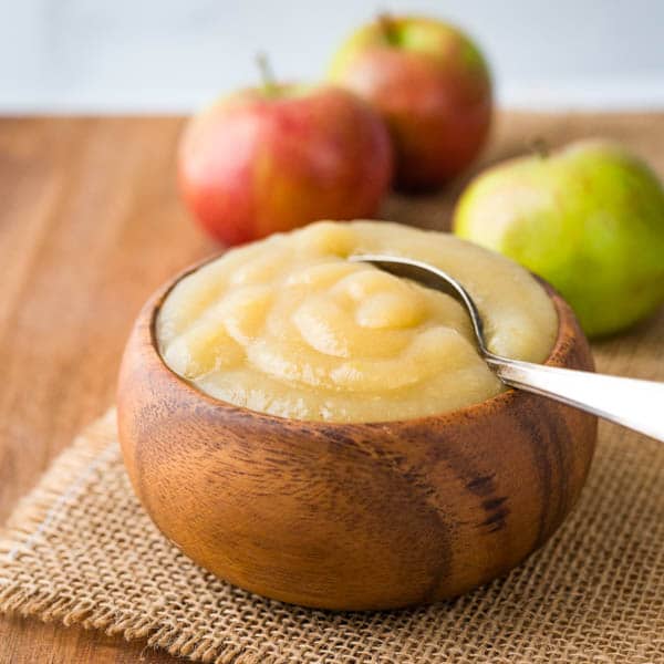 McIntosh applesauce in a wooden bowl with a spoon.