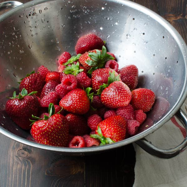 strawberries and raspberries in a colander