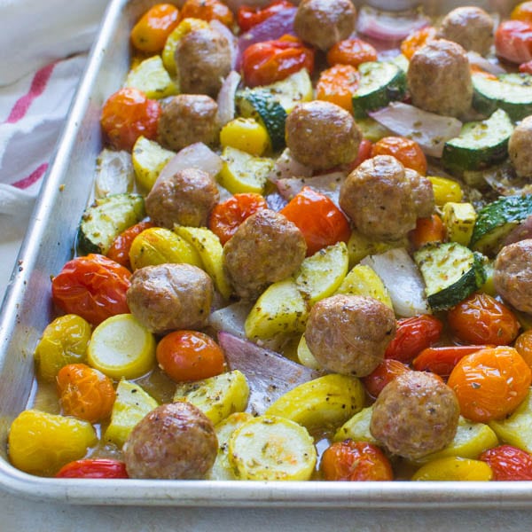 roasted vegetables and sausage on a sheet pan.