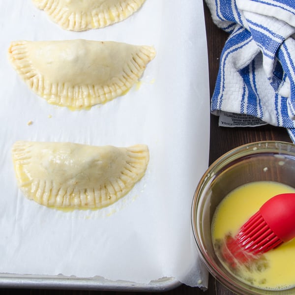 brushing Smoky Turkey Empanadas with egg wash.