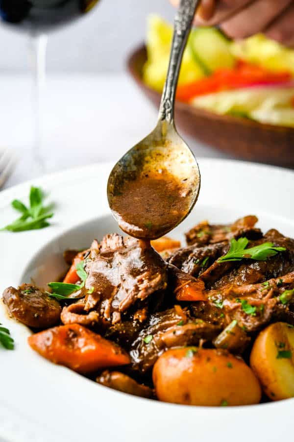 spooning porcini sauce over the pot roast.