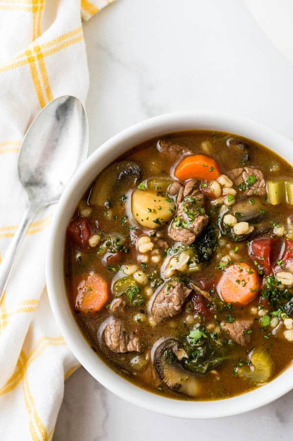 A hearty bowl of classic beef barley soup in a bowl with a spoon.