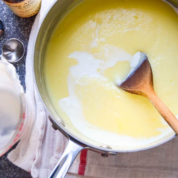 ice cream custard being cooked in a pot with a wooden spoon.