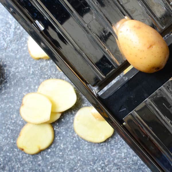 thinly slicing potatoes on a mandoline.