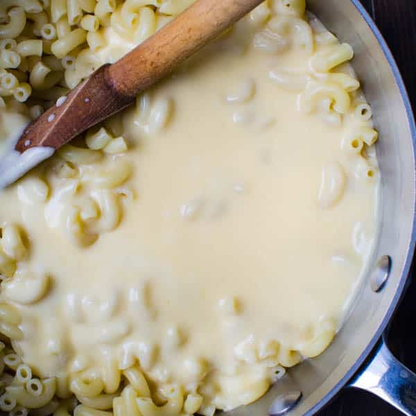 mixing macaroni with the cheese sauce.
