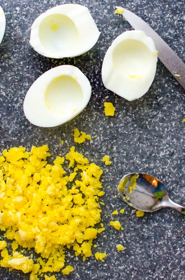 Halving the hard boiled eggs and chopping the yolks.