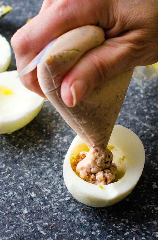 filling egg white halves with deviled ham.