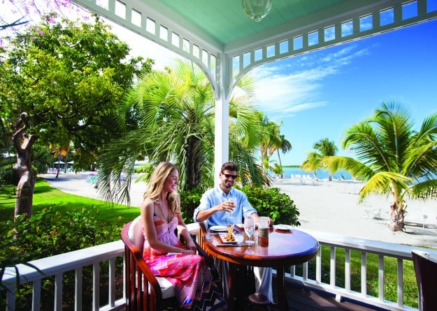 al fresco dining on a covered patio with palm trees and blue skies.