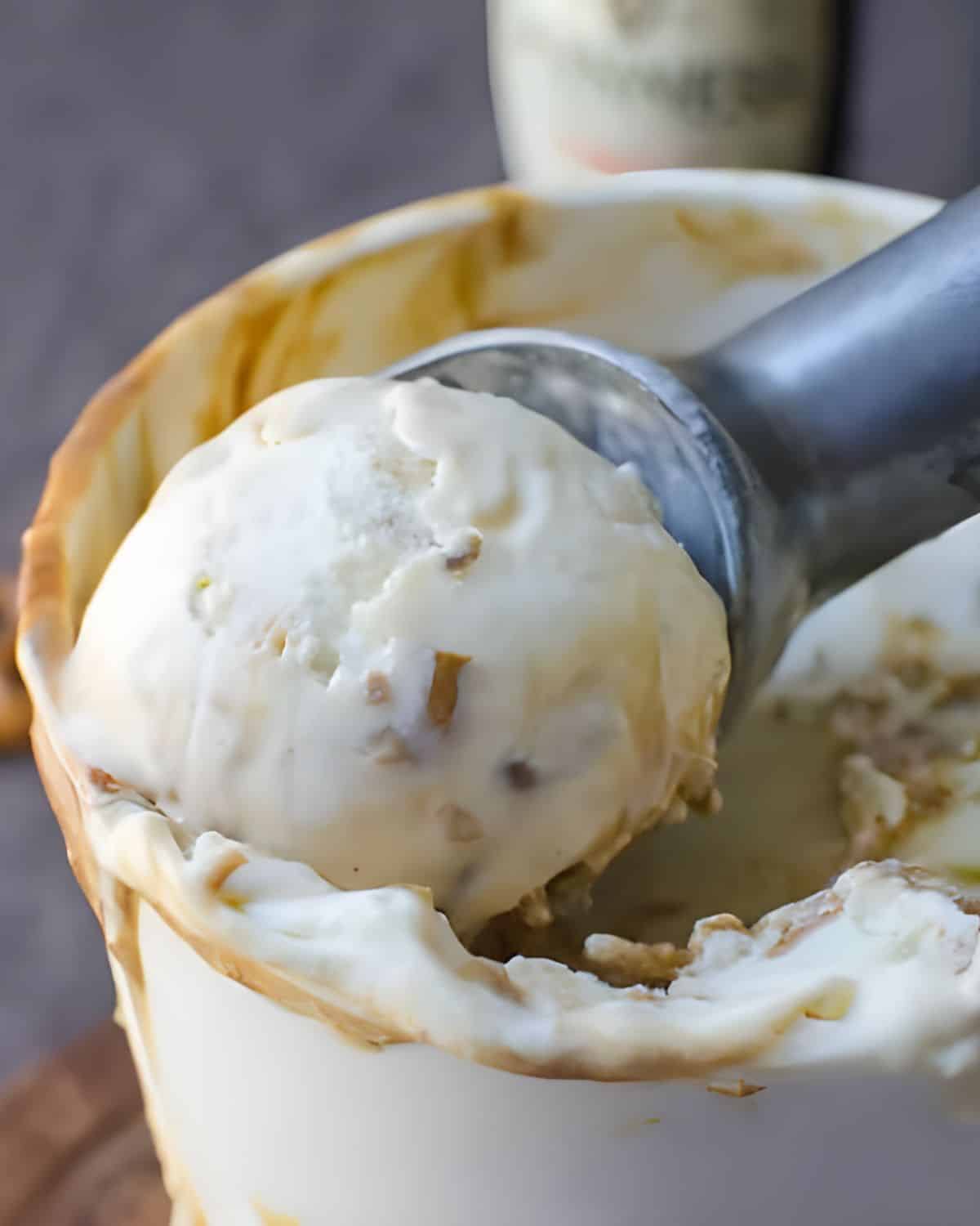 Scooping Stout caramel ice cream from a container.
