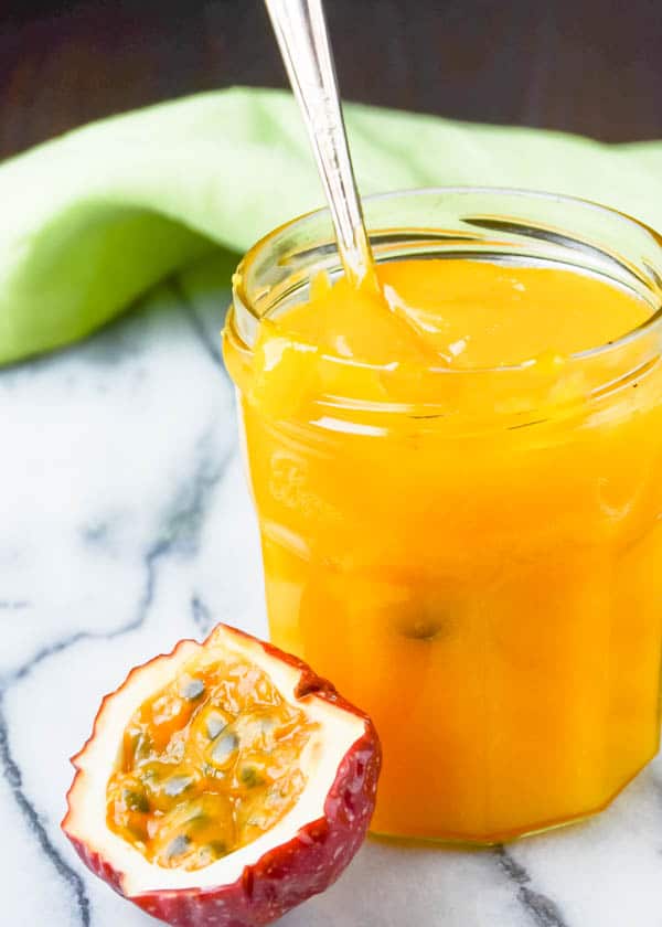 Sweet Tart Passion Fruit Curd in a jar with spoon.
