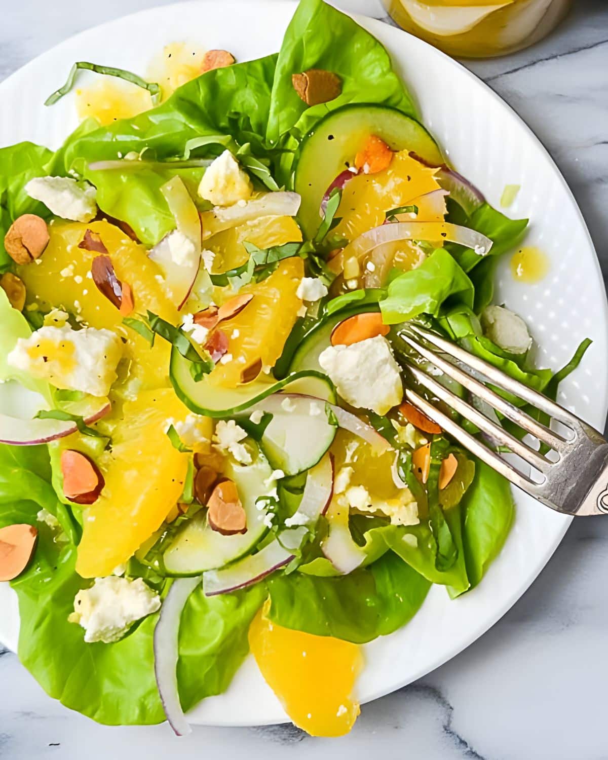 A green salad with orange segments and sliced almonds.