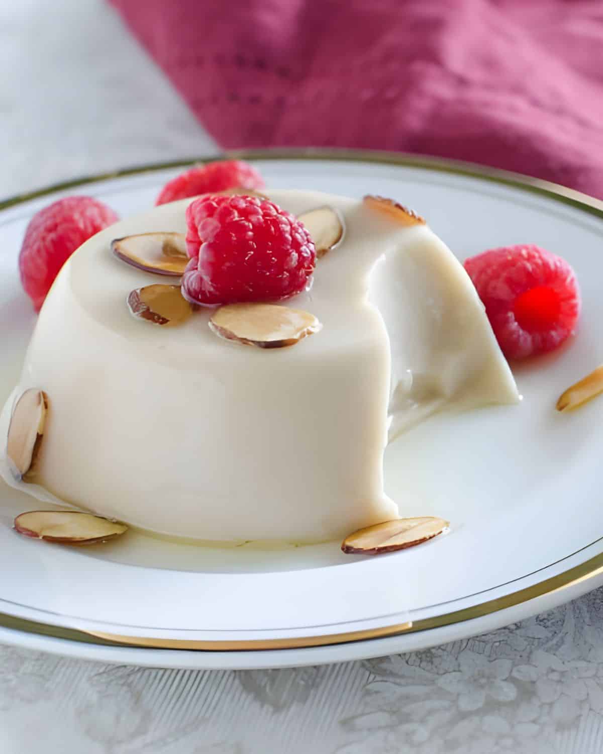 Toasted Almond Dream Panna Cotta on a plate with raspberries.