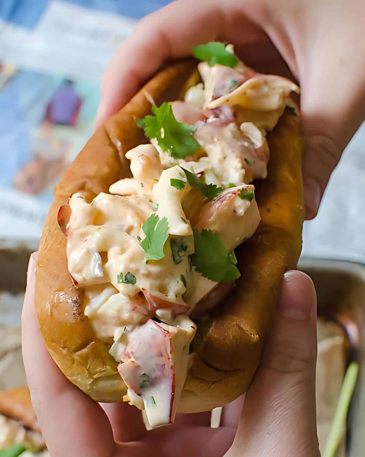 Holding a lobster roll with two hands.