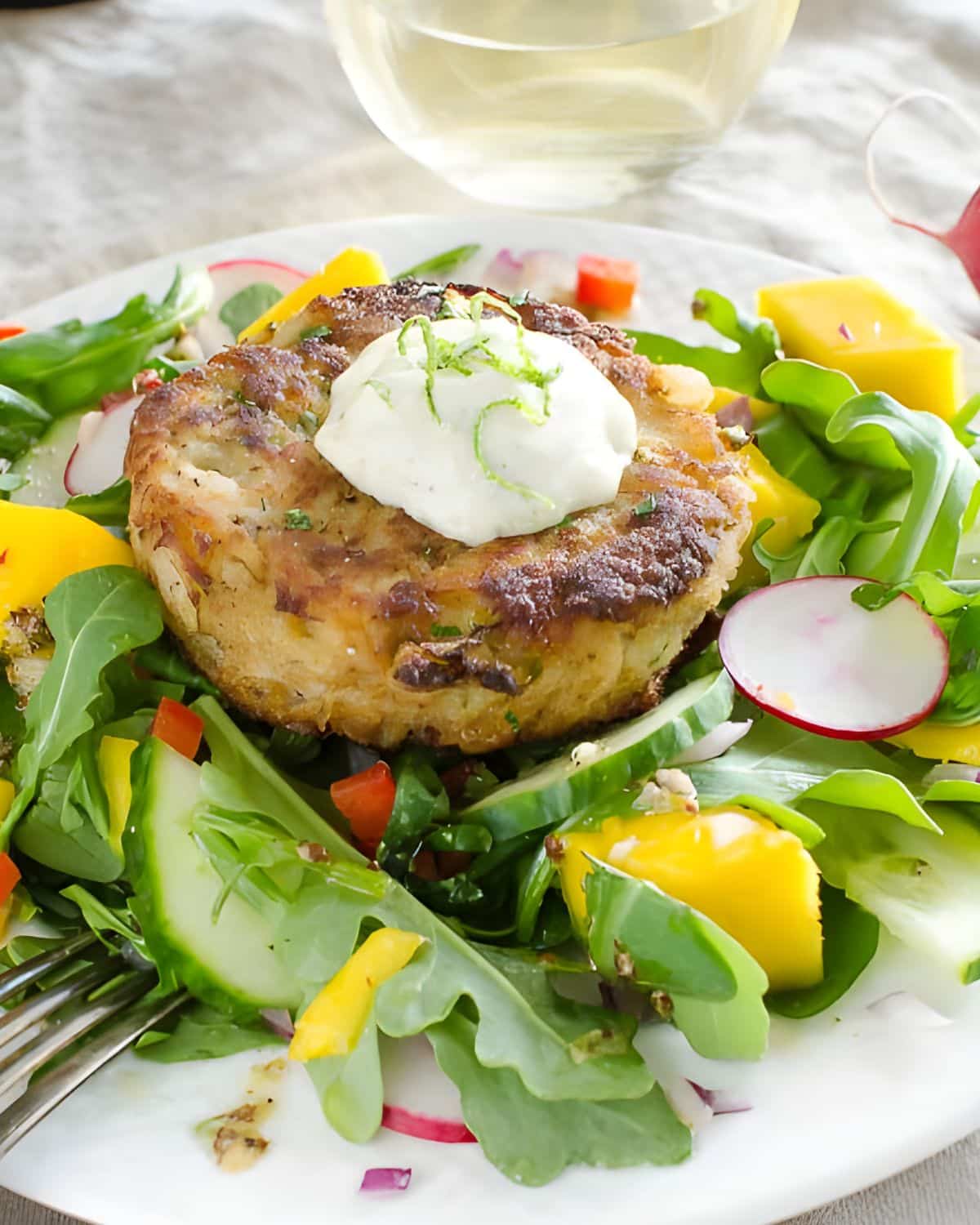 Key lime mango and crab cake salad on a white plate.