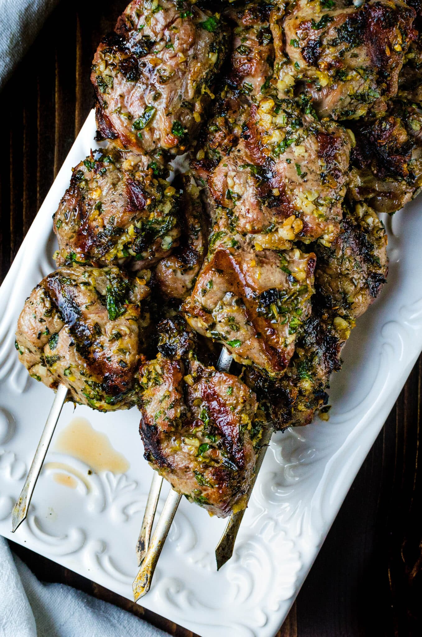 Grilled lamb kebabs on a white platter.