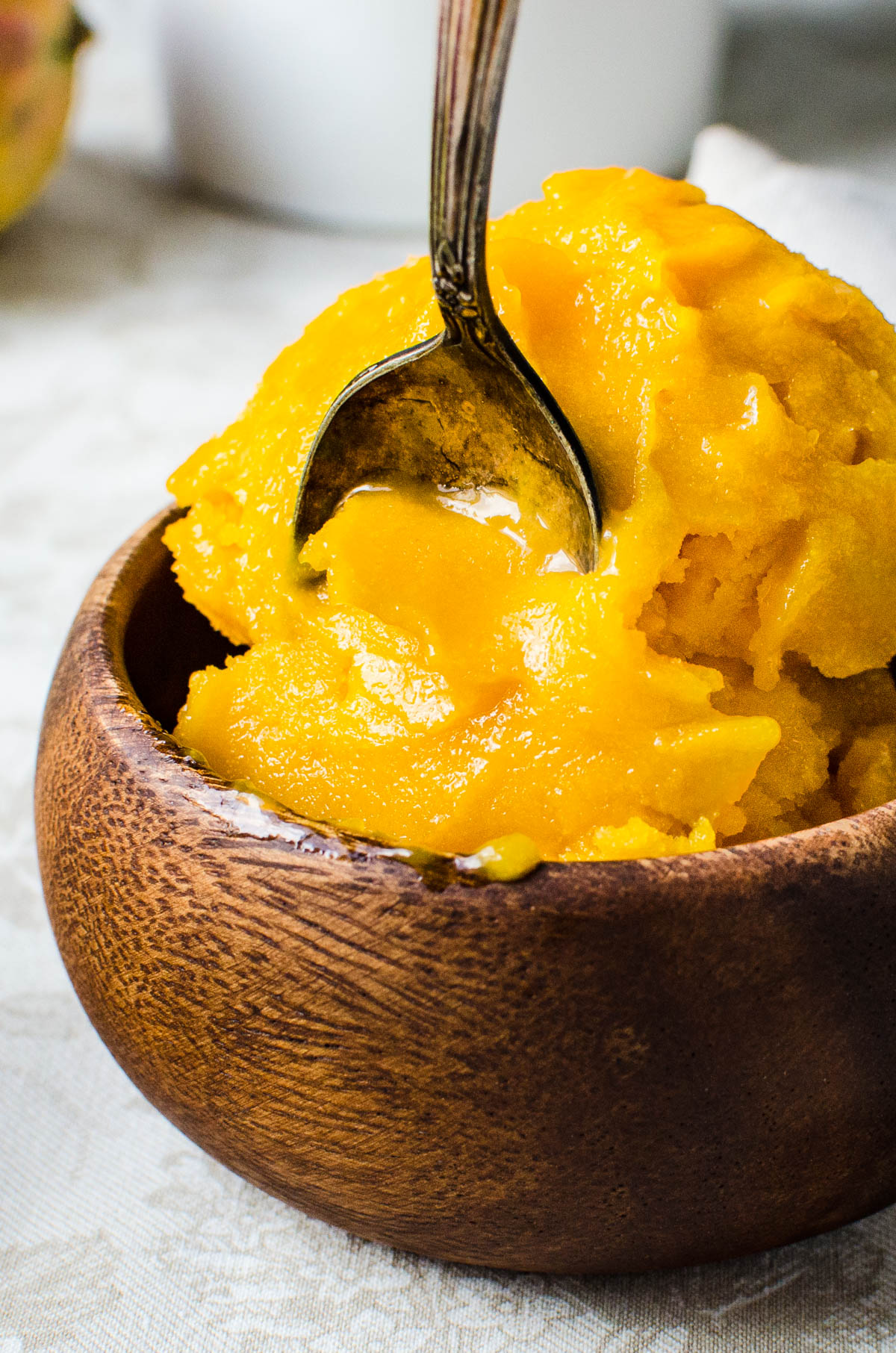 scooping mango sorbet with a spoon.
