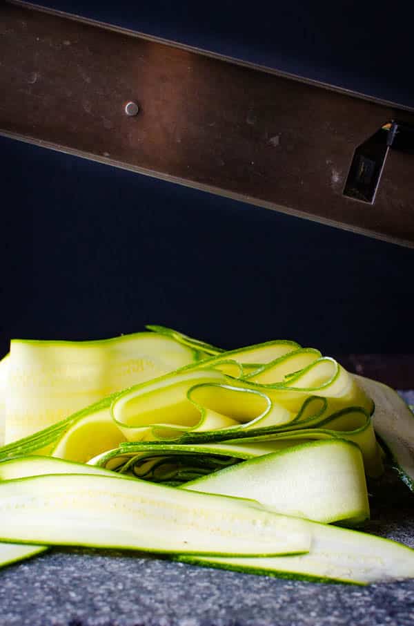 thinly sliced zucchini ribbons on a cutting board.