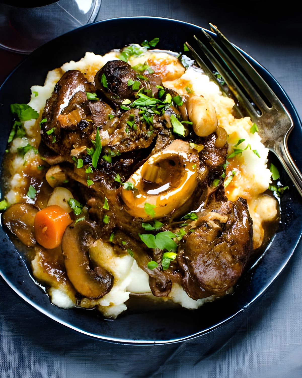 A plate of braised veal shanks over mashed potatoes.
