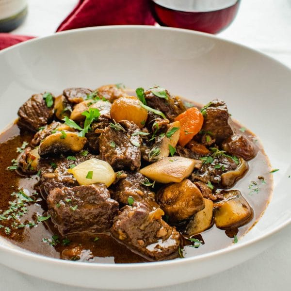 A serving of boeuf bourguignon in a dish with red wine.