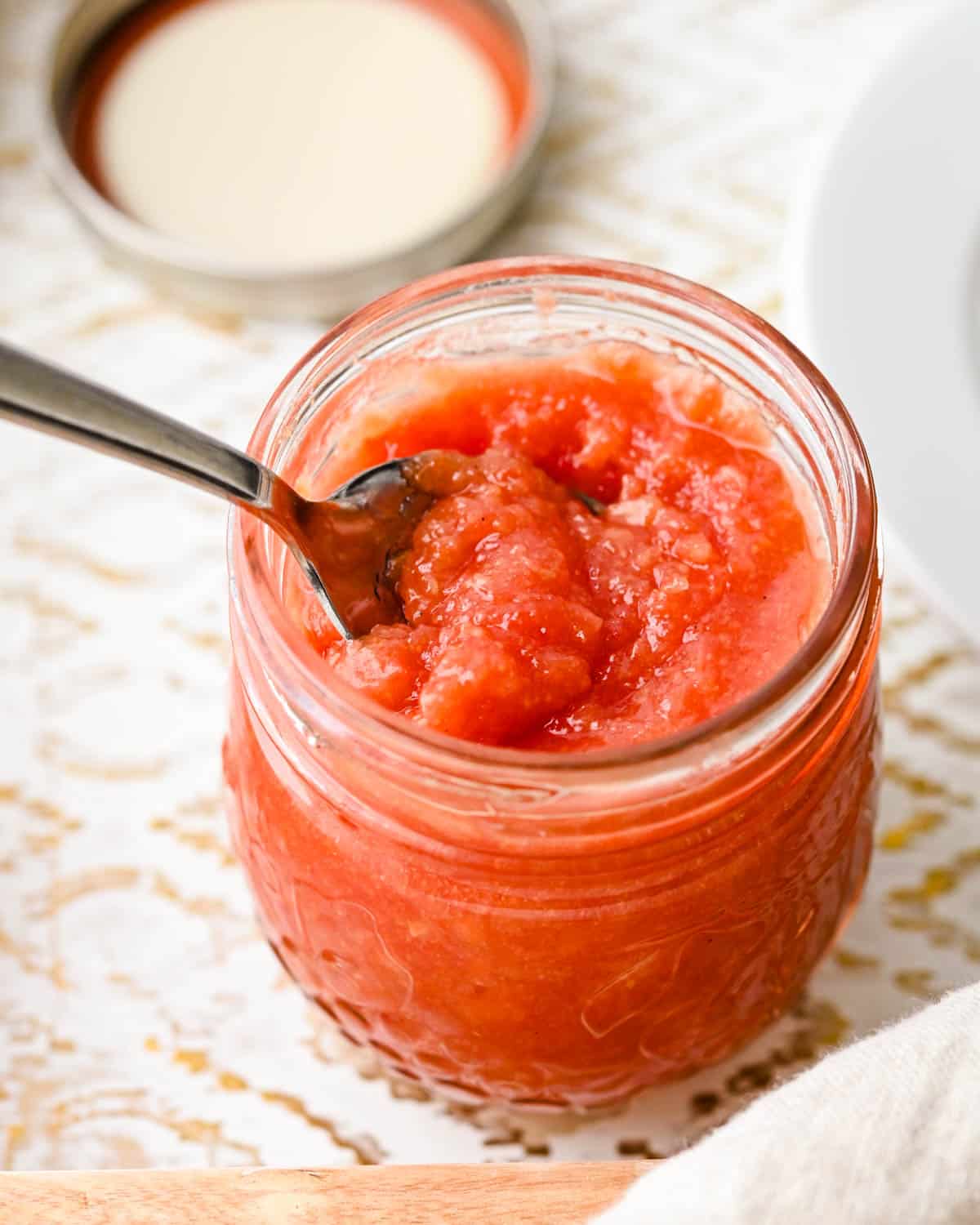 a jar of guava jam with a spoon to scoop it up.