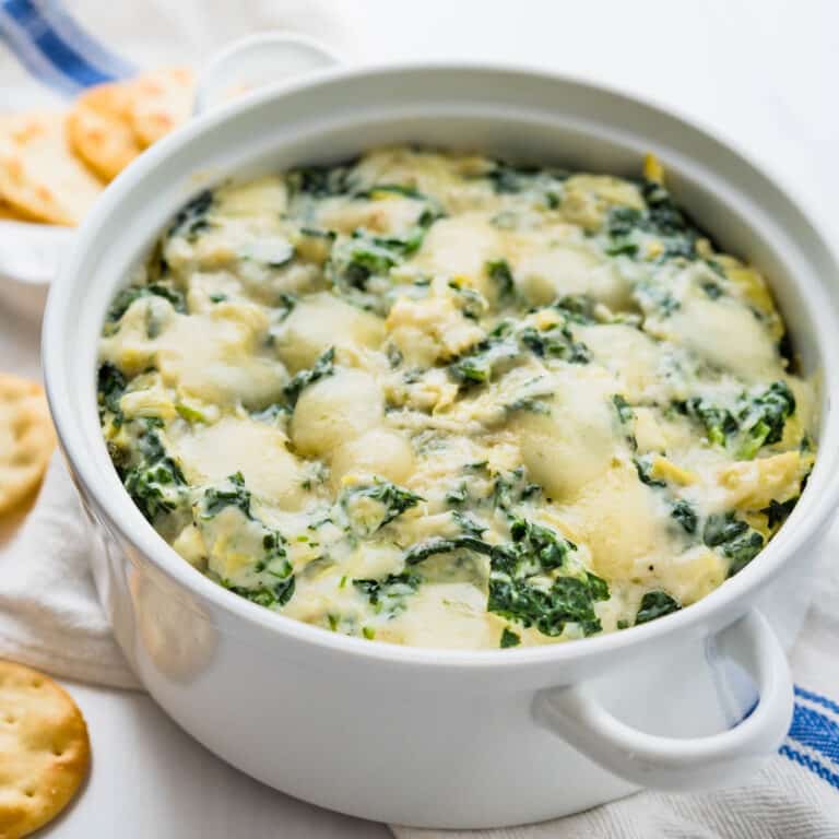 a bubbly warm spinach artichoke dip in a white baking dish.