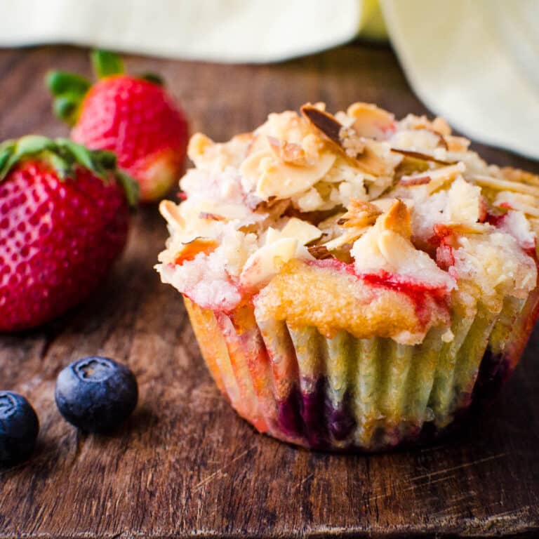 Mixed berry muffins with strawberries and blueberries on the side.