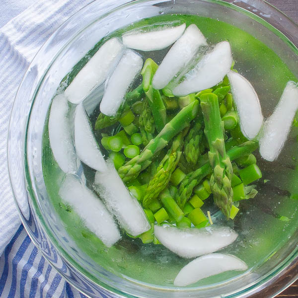 Shocking blanched asparagus in an ice bath.