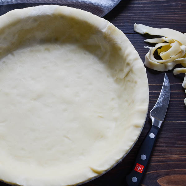 pie pastry in a pie plate with a knife and scraps.